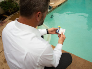 man testing pool water