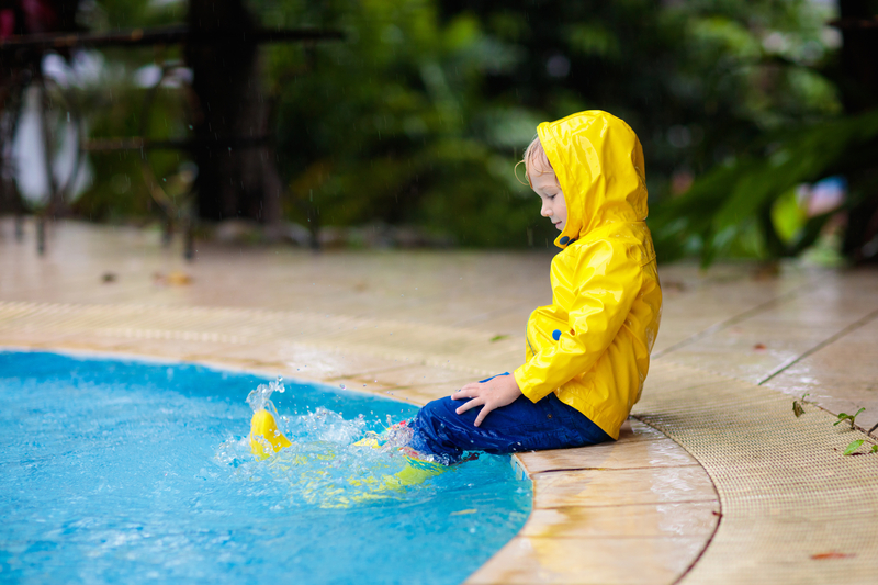 Child playing in pool during a rain storm.